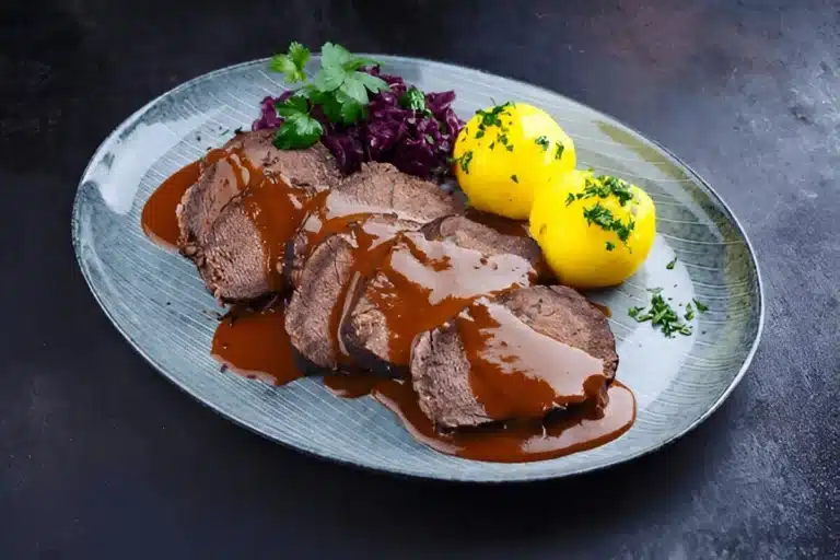 Sauerbraten en tranches servi avec boulettes de pommes de terre et chou rouge