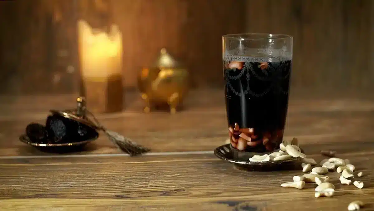 Boisson Jallab dans une ambiance orientale Verre de Jallab posé sur une table en bois avec des noix de cajou et une ambiance chaleureuse.