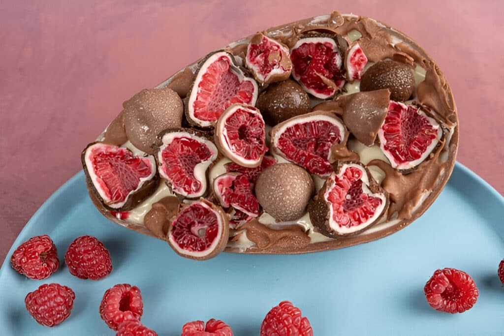 Œuf en chocolat garni de framboises et bonbons au chocolat.