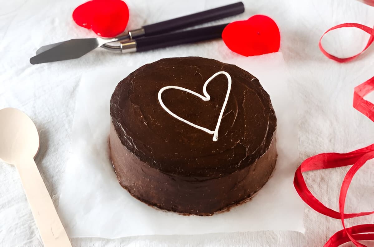 Bento cake au chocolat dans une boîte blanche, décoré d’un cœur en crème.