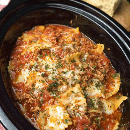 Crockpot lasagna with melted cheese, meat sauce, and herbs in a slow cooker
