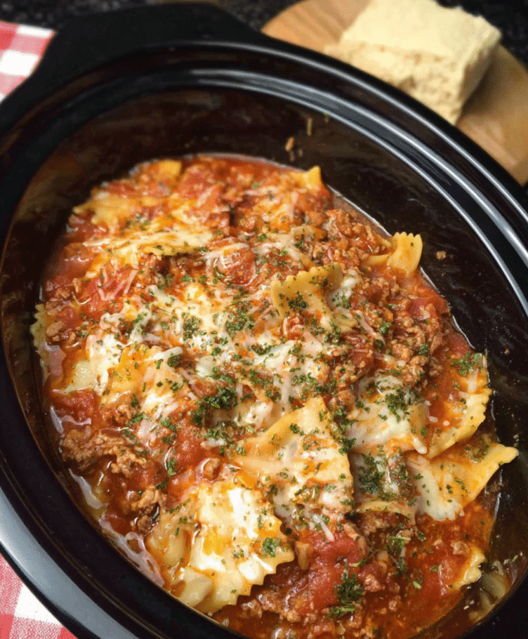 Crockpot lasagna with melted cheese, meat sauce, and herbs in a slow cooker