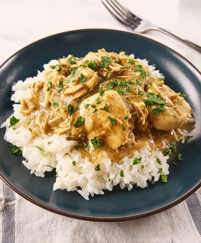 Close-up of Crockpot French Onion Meatballs served over creamy mashed potatoes, topped with caramelized onions and rich brown gravy, garnished with fresh parsley.