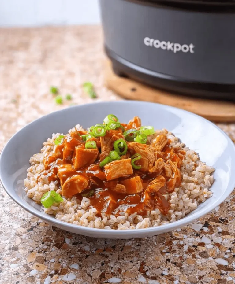 An appetizing bowl of Sweet Hawaiian Crock Pot Chicken with fluffy rice and green onions, with a Crock Pot in the blurred background.