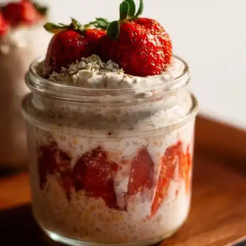 Strawberry cheesecake overnight oats topped with fresh strawberries and mint